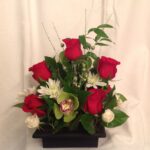 Red roses and white orchids in a black vase.