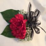 A red and black corsage with a bow.