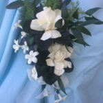 A bouquet of white and black flowers on a blue cloth.