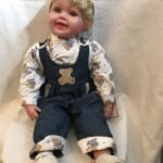 A doll wearing overalls and a teddy bear.