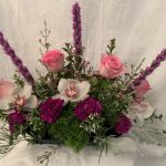 An arrangement of pink roses, orchids and greenery.