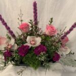 An arrangement of pink roses, orchids and greenery.